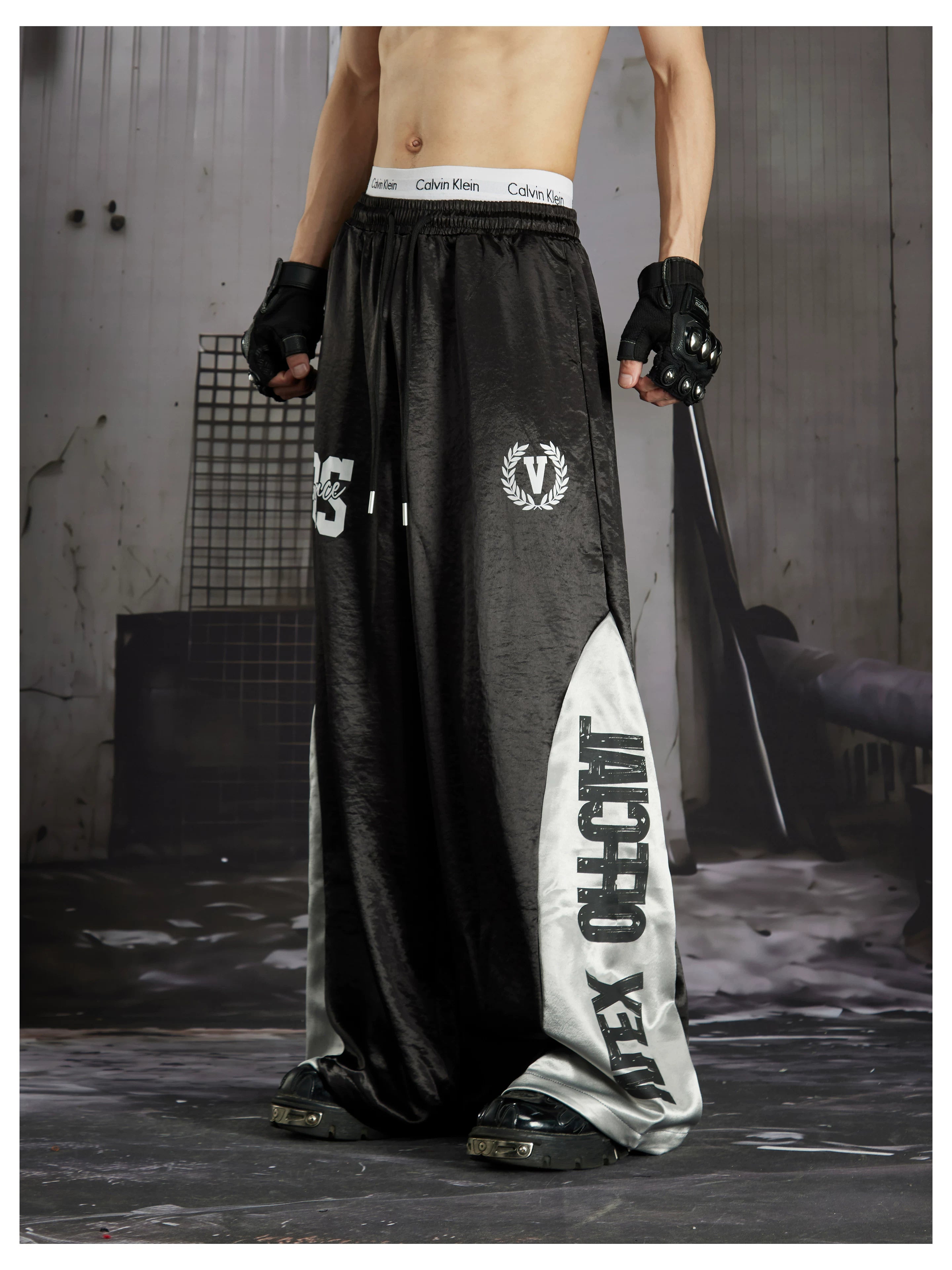 NOMANIAI Street-style casual pants featuring a draped fit, paneling, and a print design.