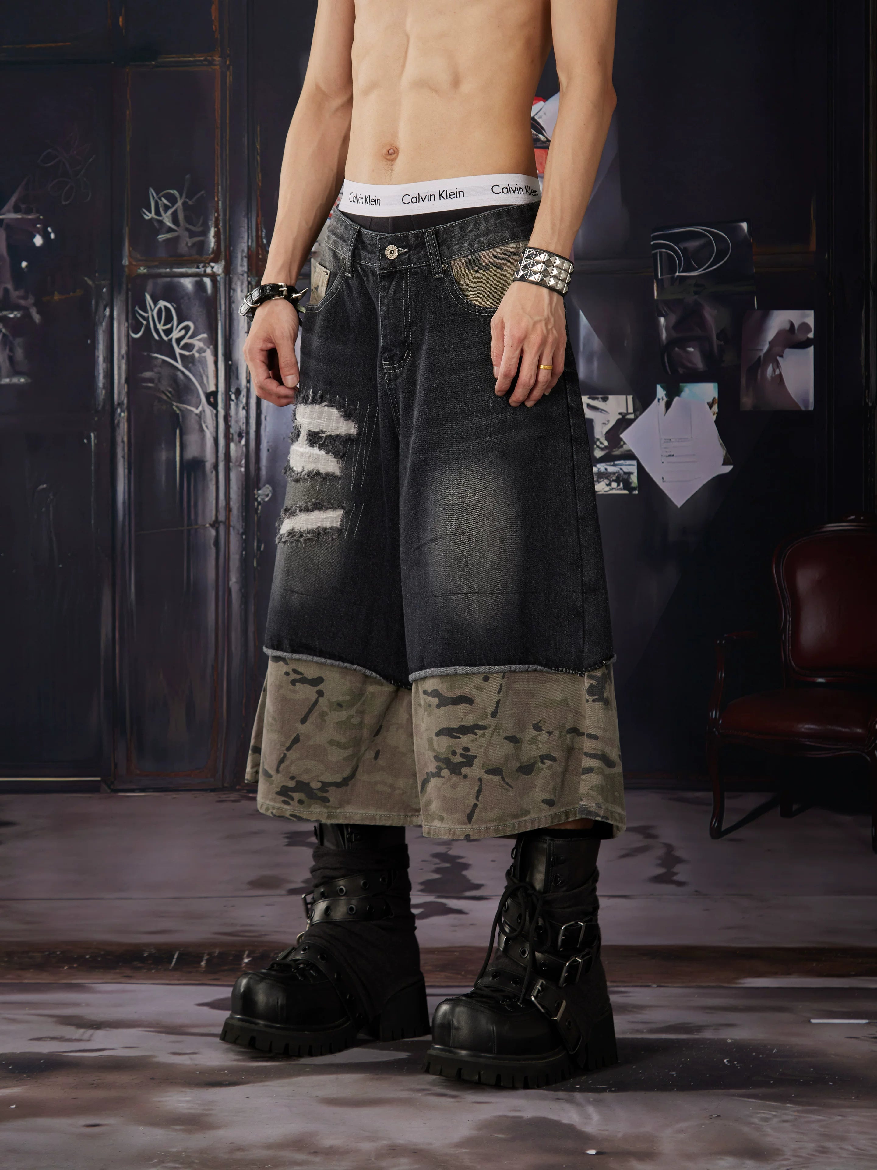 NOMANIAI Loose-fit, cropped pants featuring a "faux-layered" design, camouflage print, and a washed, distressed finish.