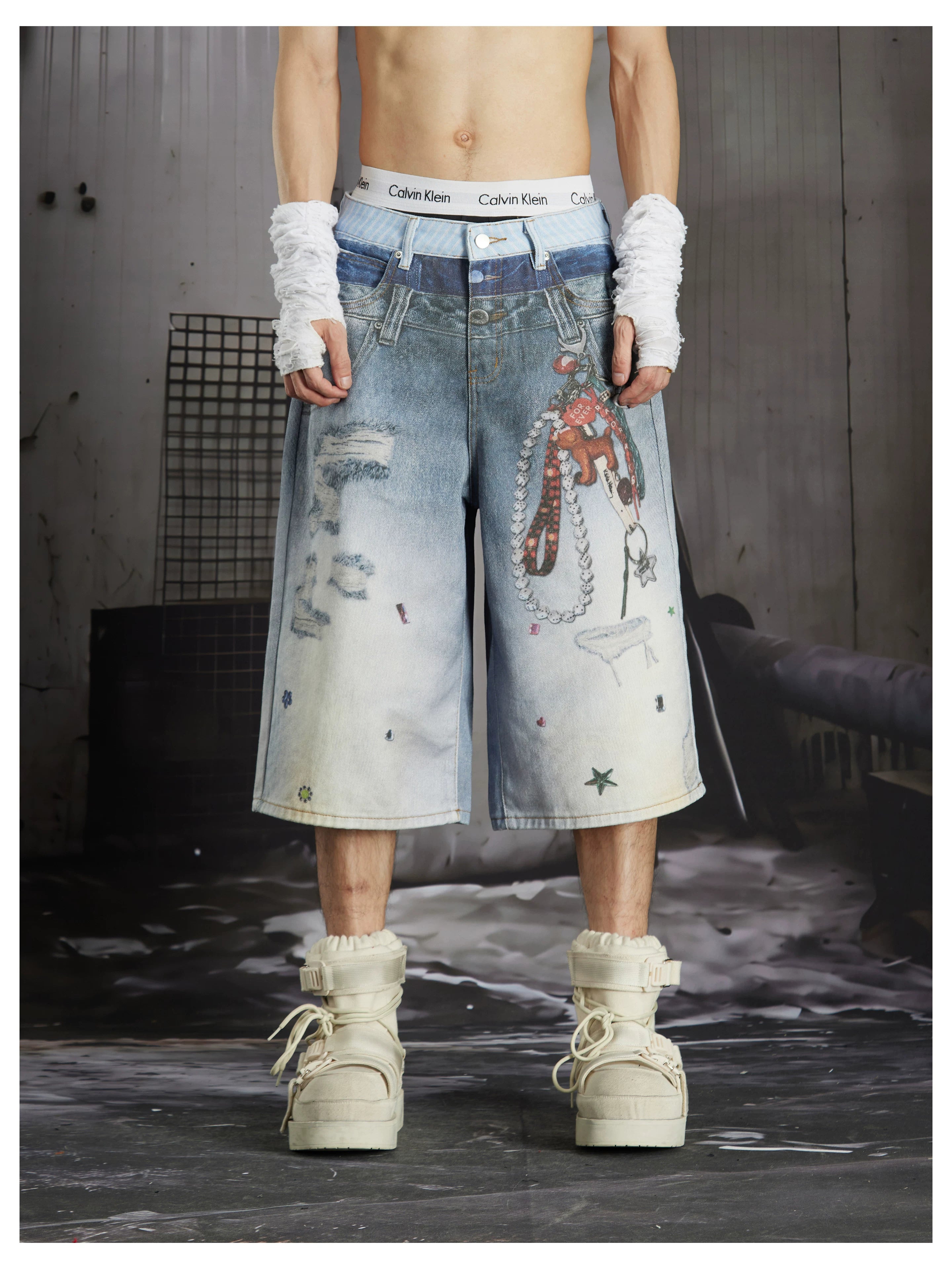 NOMANIAI Y2K-style loose-fit cropped pants featuring a triple-waistband design and chain charm detail.