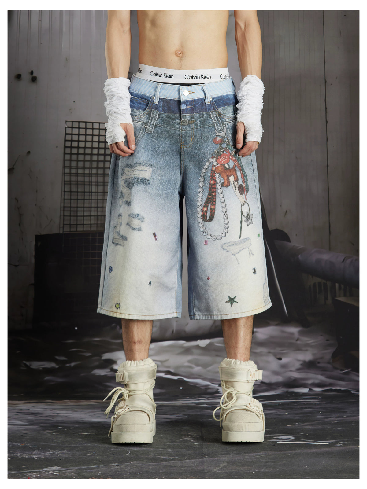 NOMANIAI Y2K-style loose-fit cropped pants featuring a triple-waistband design and chain charm detail.