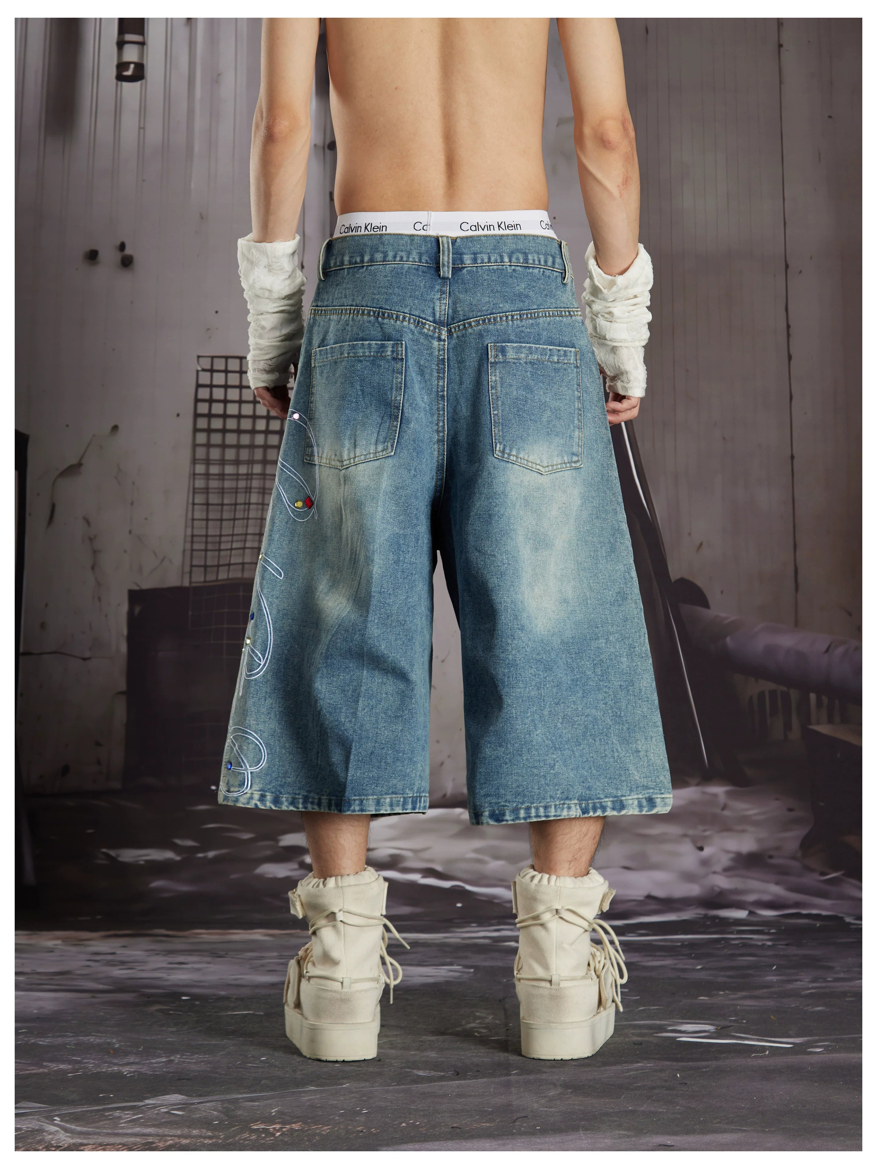 NOMANIAI Cropped jeans with rhinestone and embroidery totem design.