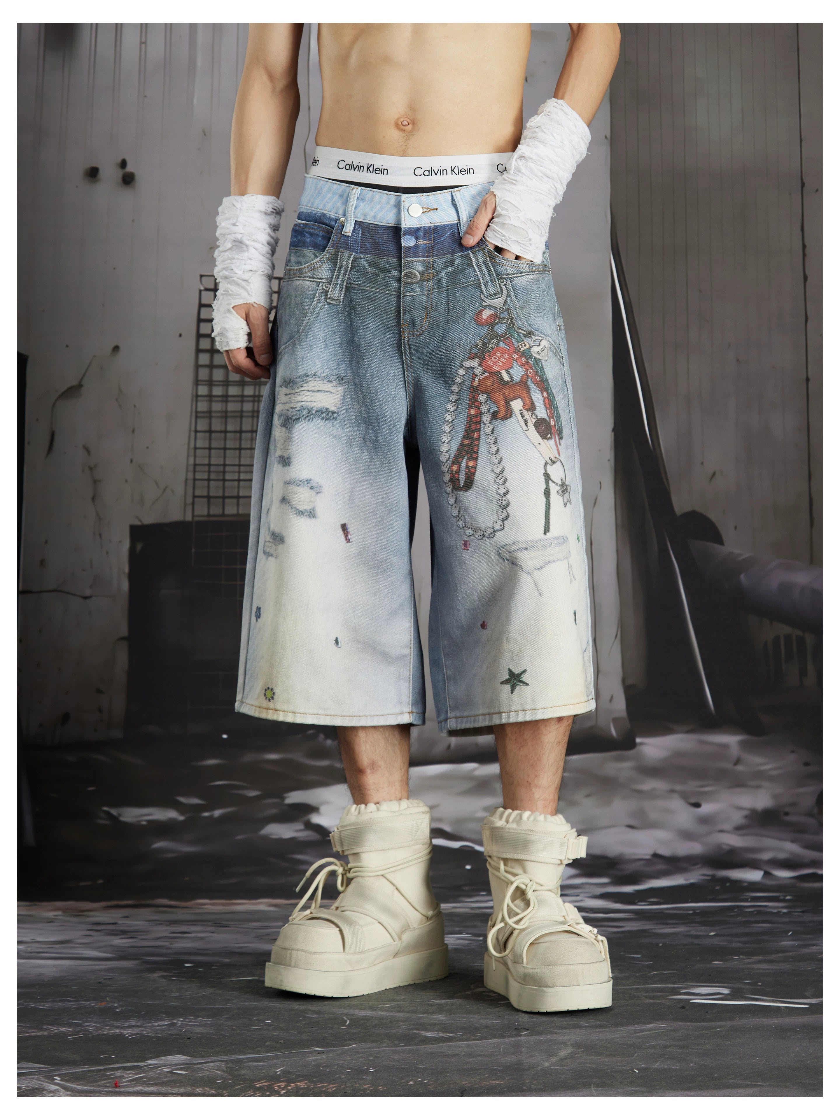 NOMANIAI Y2K-style loose-fit cropped pants featuring a triple-waistband design and chain charm detail.