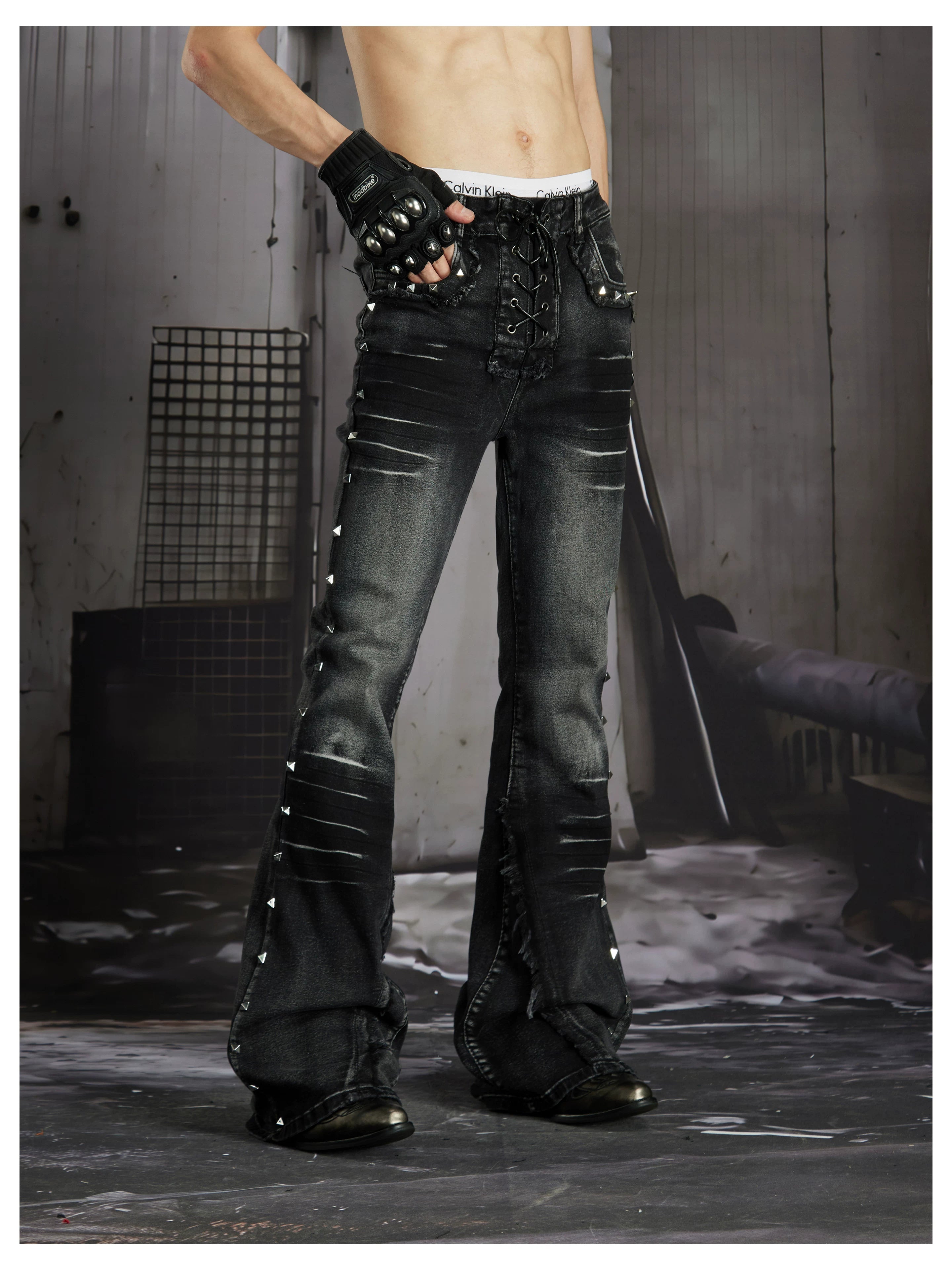 NOMANIAI Distressed, slim-fit, slight-flare jeans with studs—dark streetwear style.