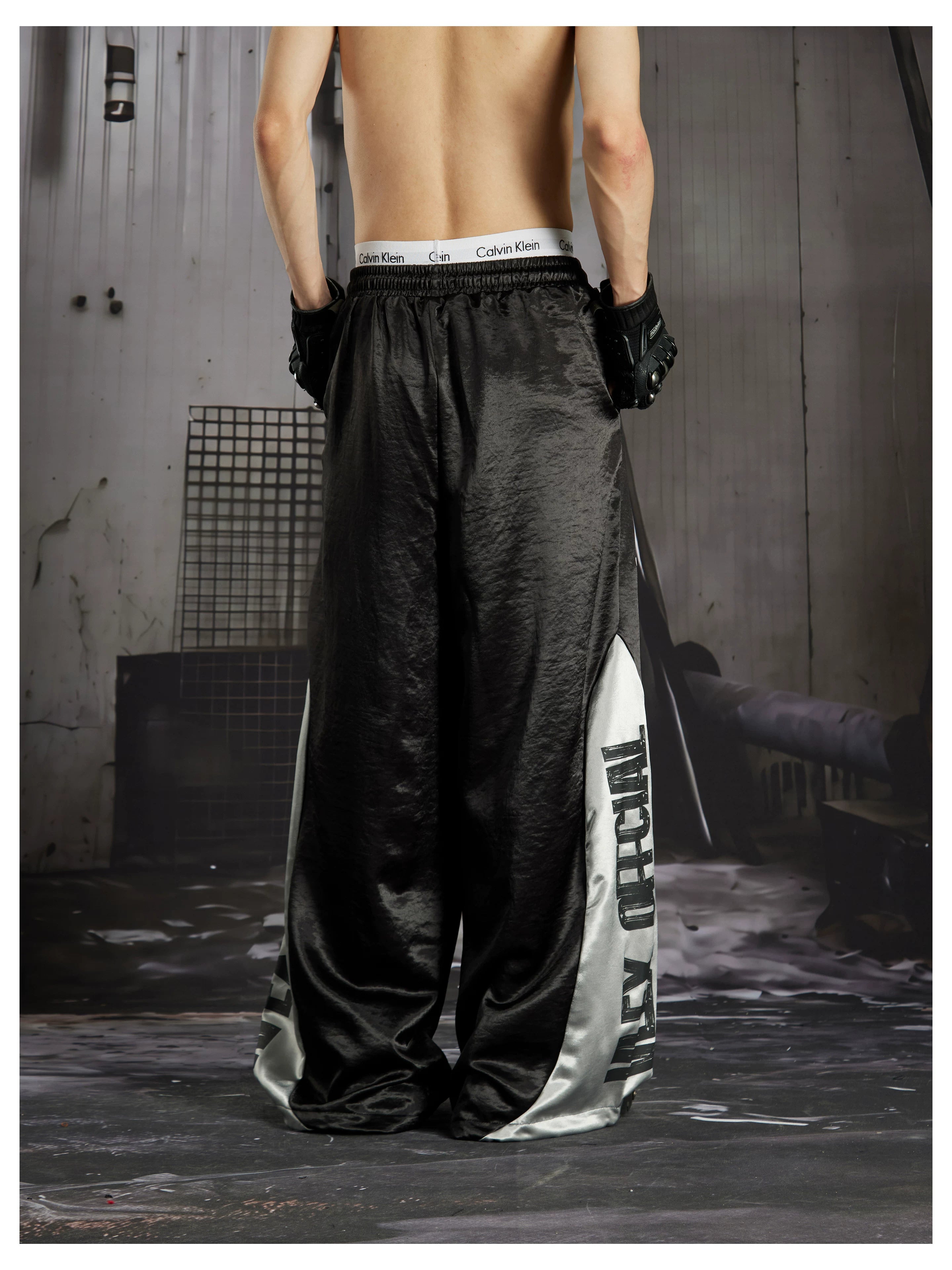 NOMANIAI Street-style casual pants featuring a draped fit, paneling, and a print design.