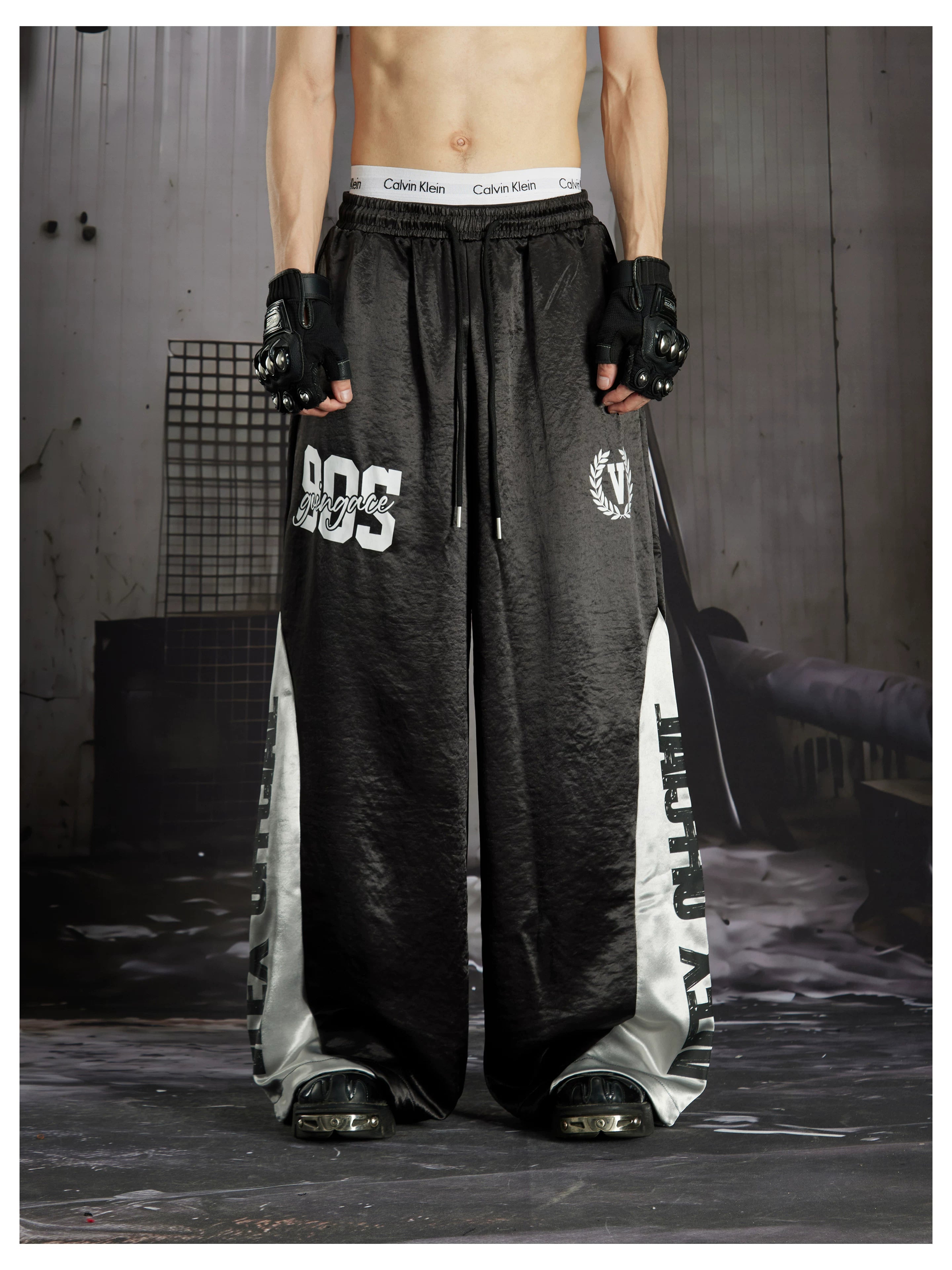 NOMANIAI Street-style casual pants featuring a draped fit, paneling, and a print design.