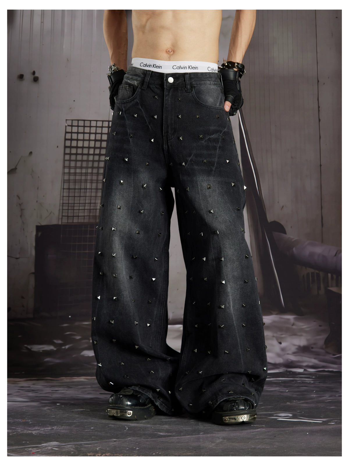 NOMANIAI  Loose-fit, acid-washed, distressed denim jeans with square studs—streetwear style.