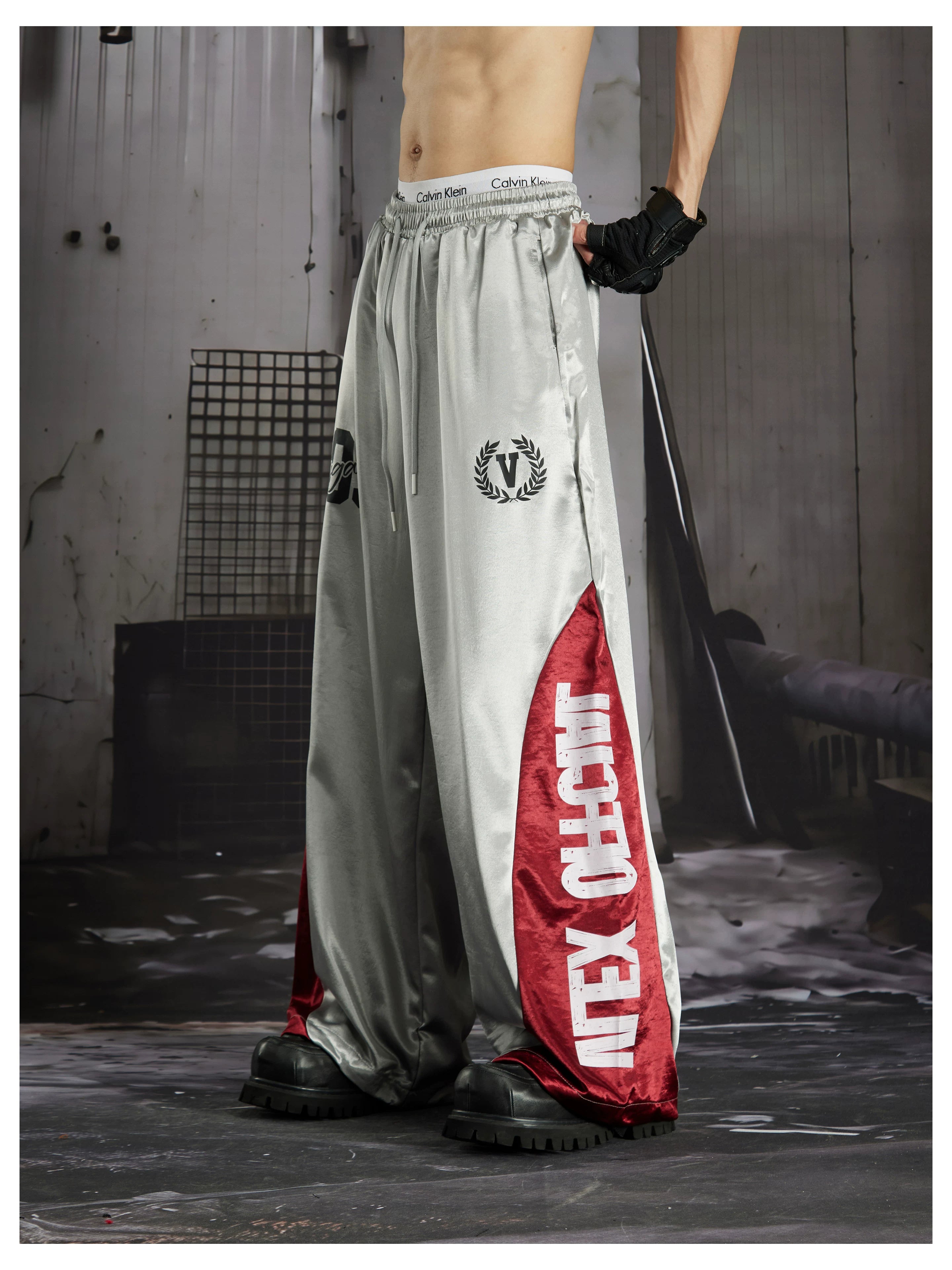 NOMANIAI Street-style casual pants featuring a draped fit, paneling, and a print design.