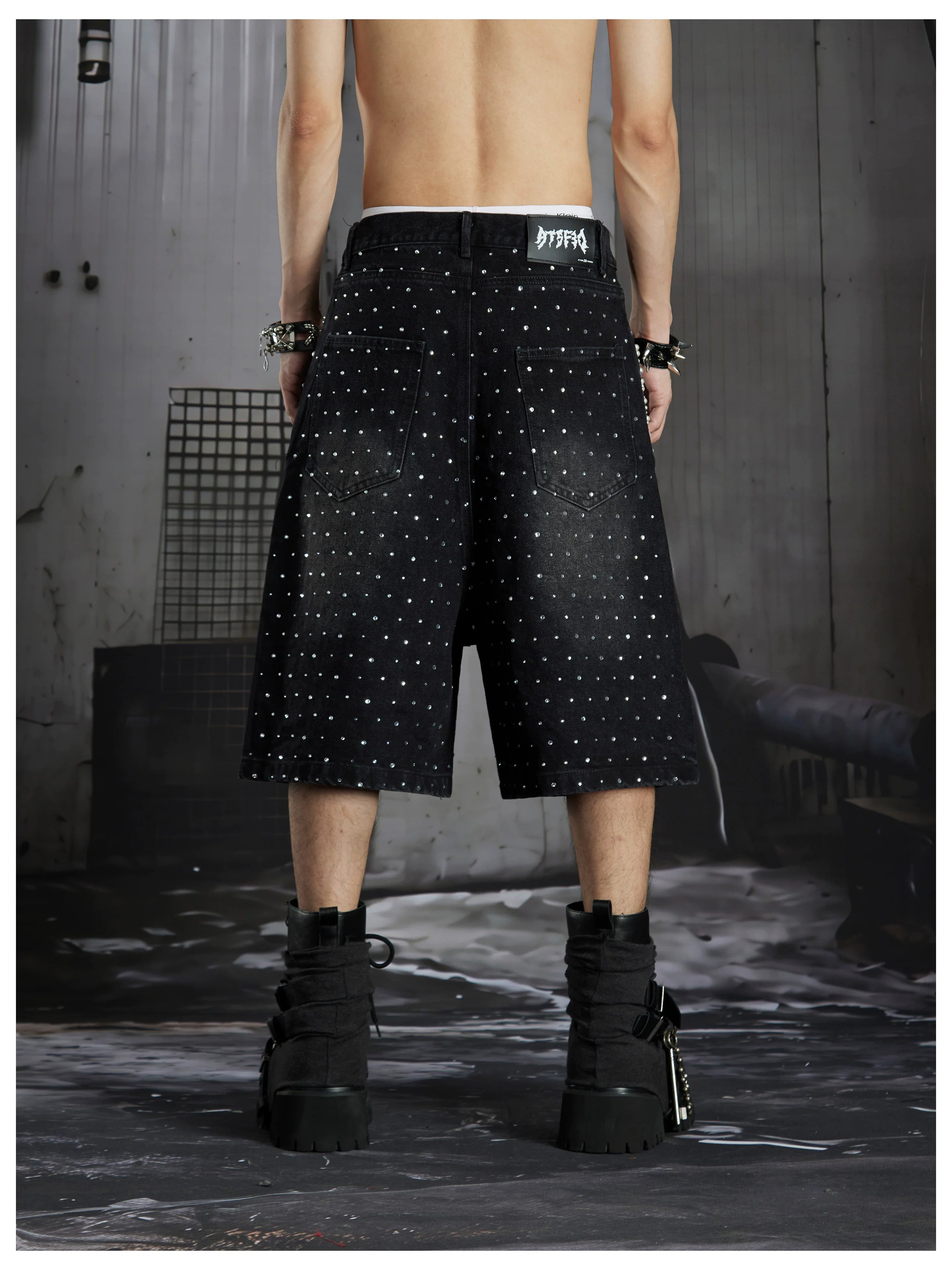 NOMANIAI  Oversized, cropped, studded denim jeans with a punk-style distressed wash.