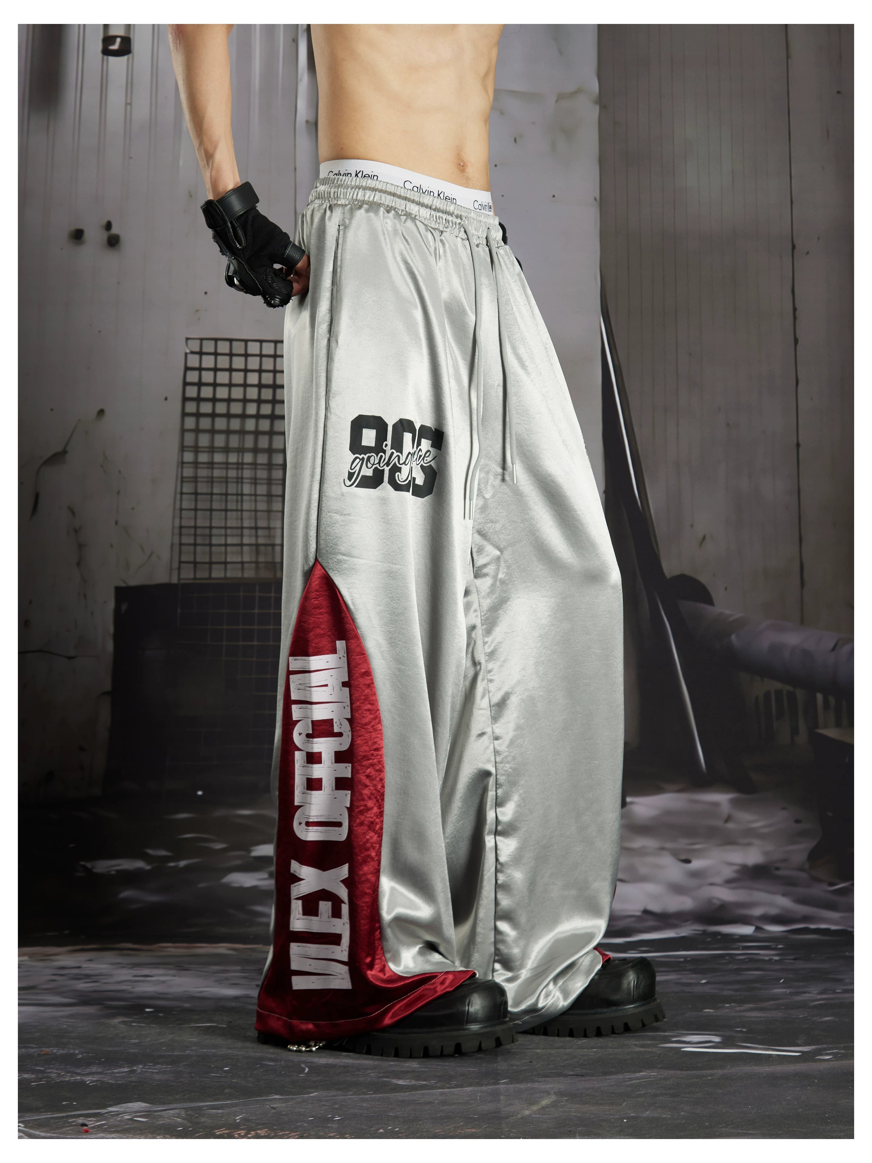 NOMANIAI Street-style casual pants featuring a draped fit, paneling, and a print design.