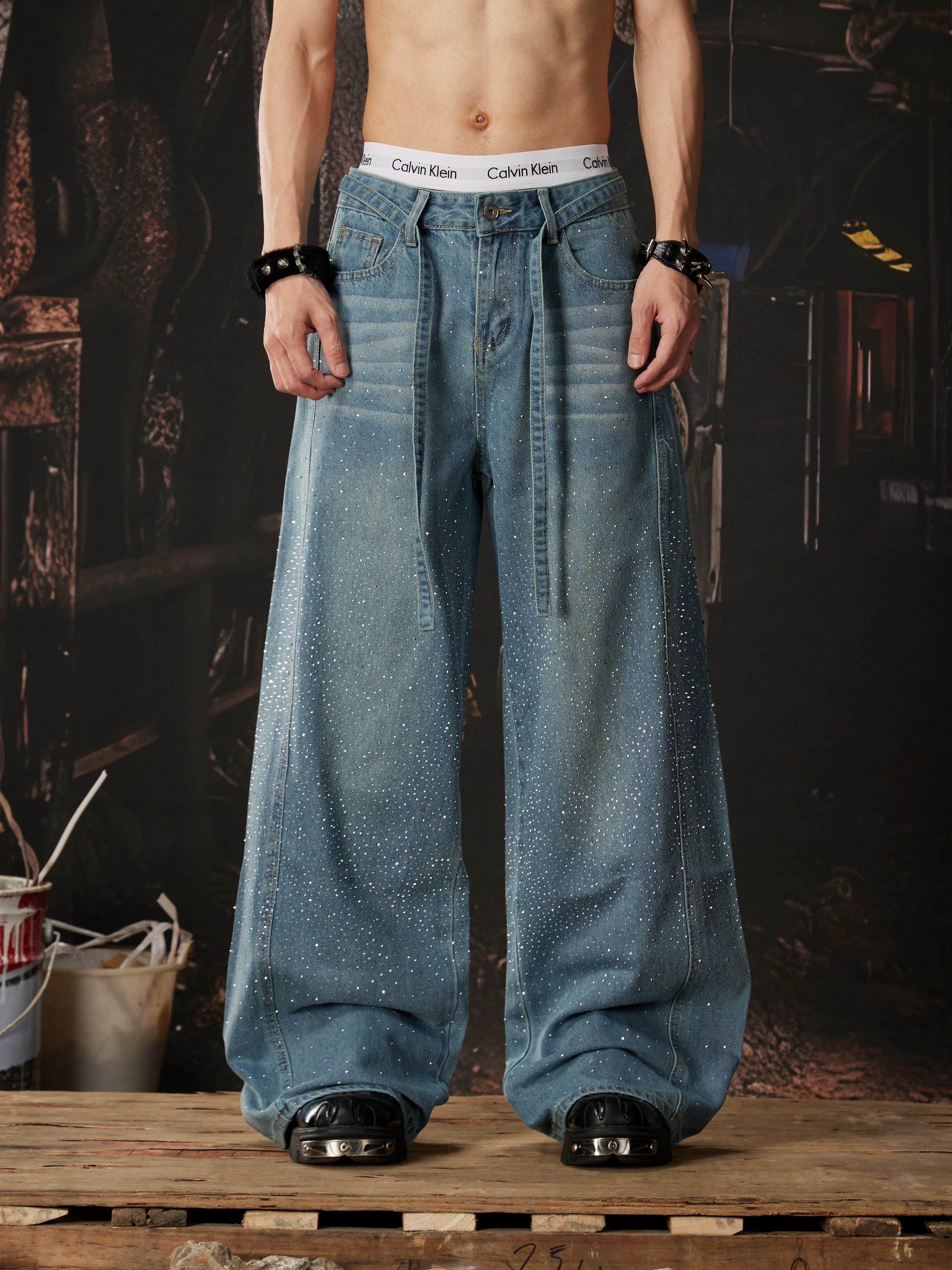 NOMANIAI  Loose-fit, acid-washed, distressed denim jeans featuring rhinestone-studded streamers.