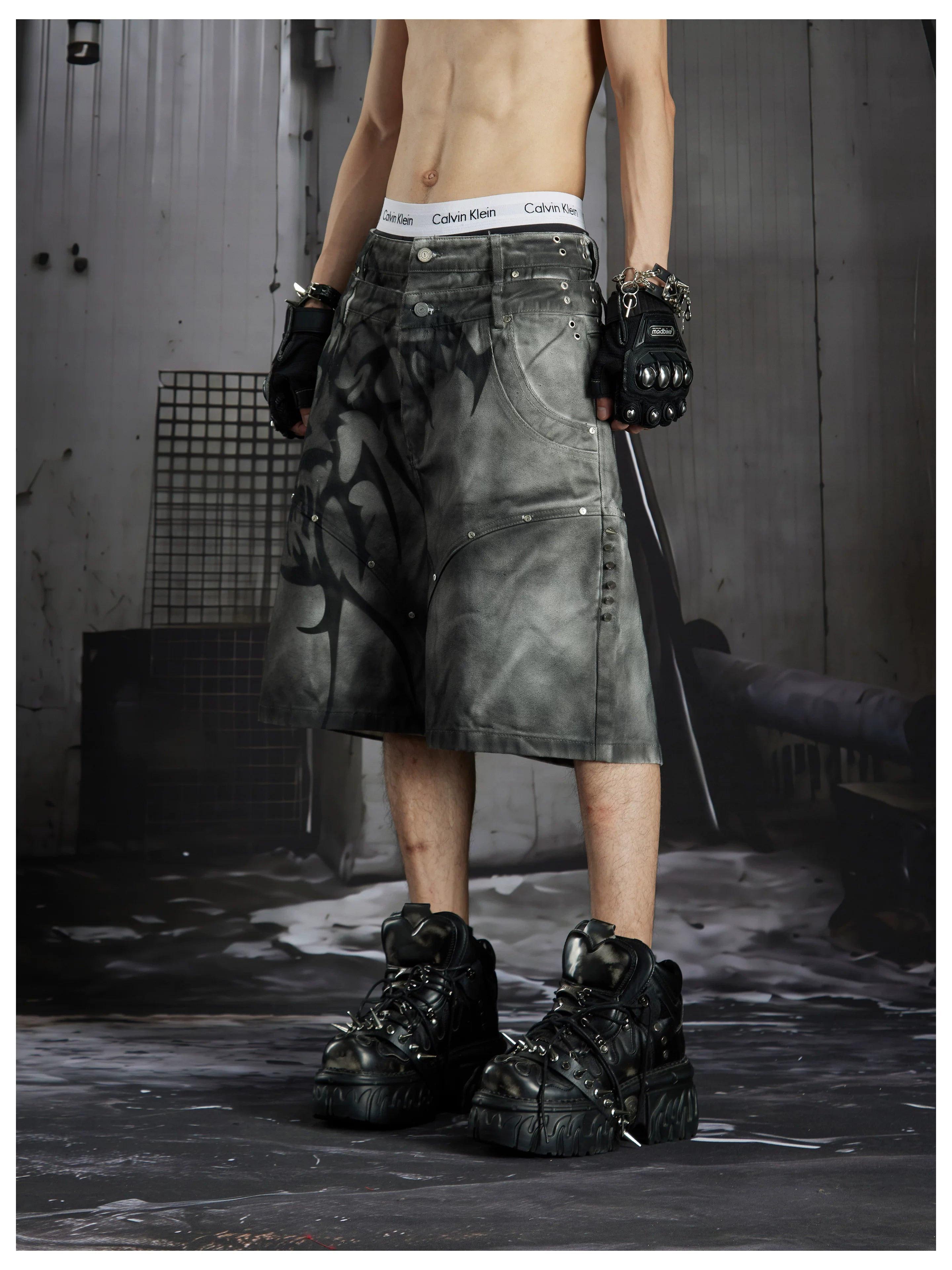 NOMANIAI Y2K loose-fit denim shorts with hand-drawn motifs and studs.