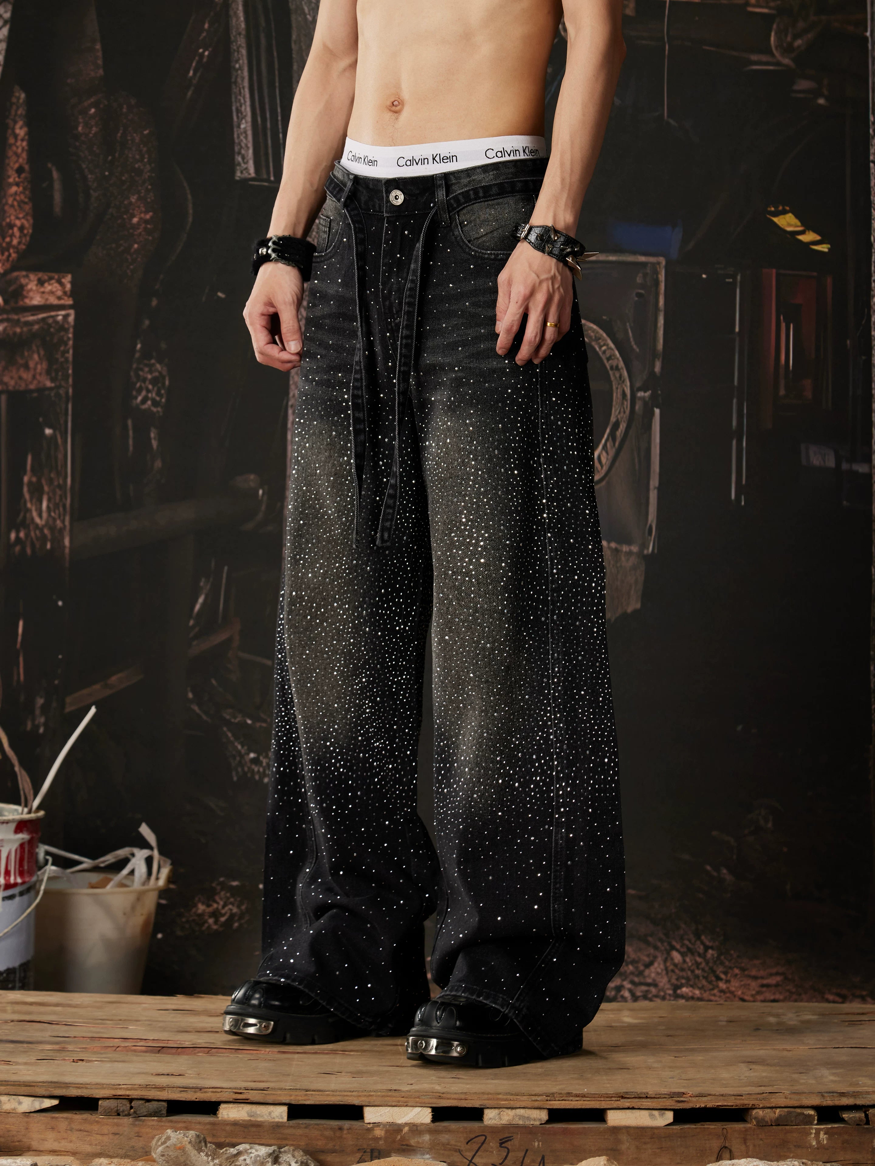 NOMANIAI  Loose-fit, acid-washed, distressed denim jeans featuring rhinestone-studded streamers.