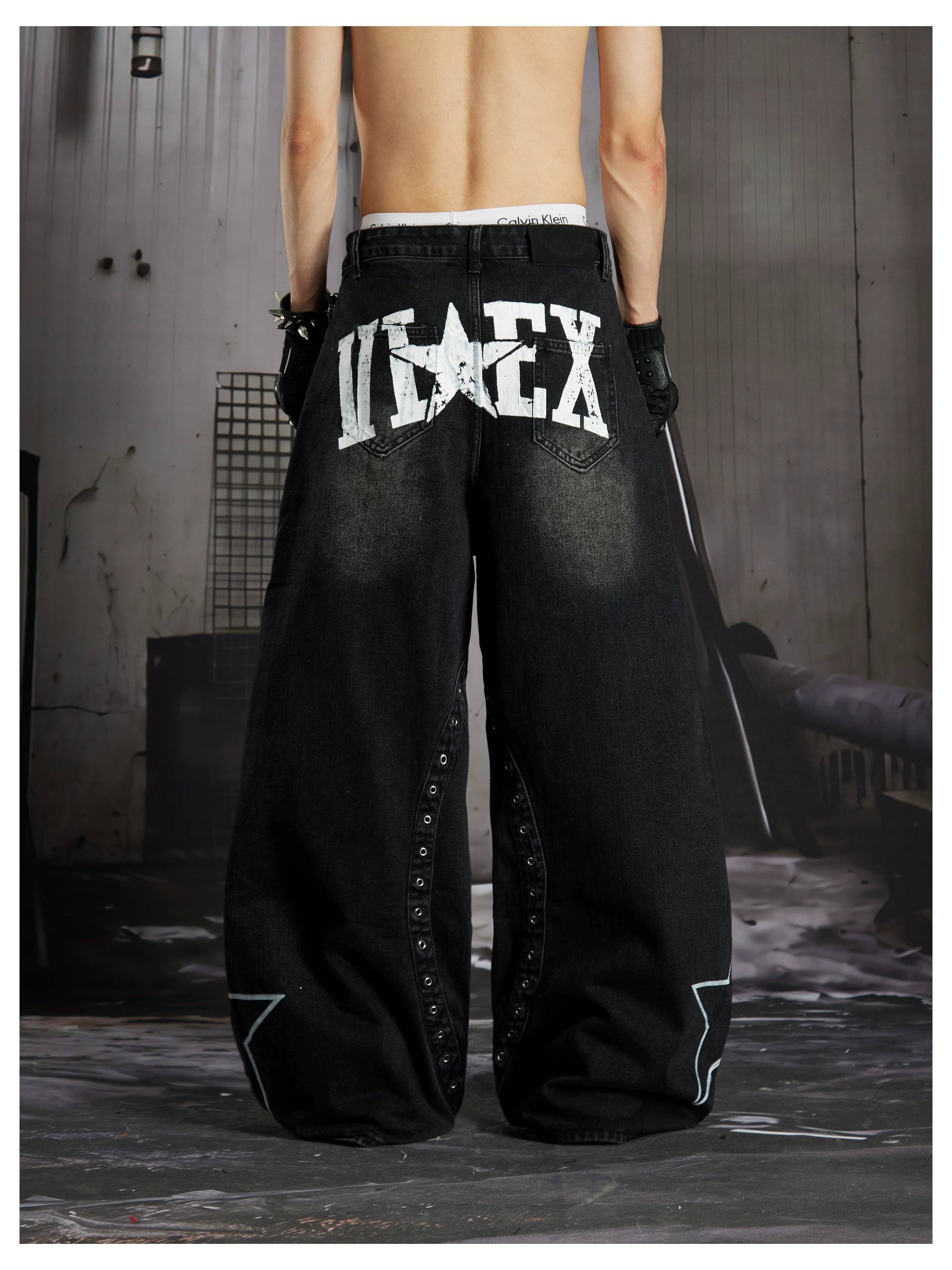 NOMANIAI  Hand-painted star and stud detail wide-leg jeans with a washed, distressed finish.