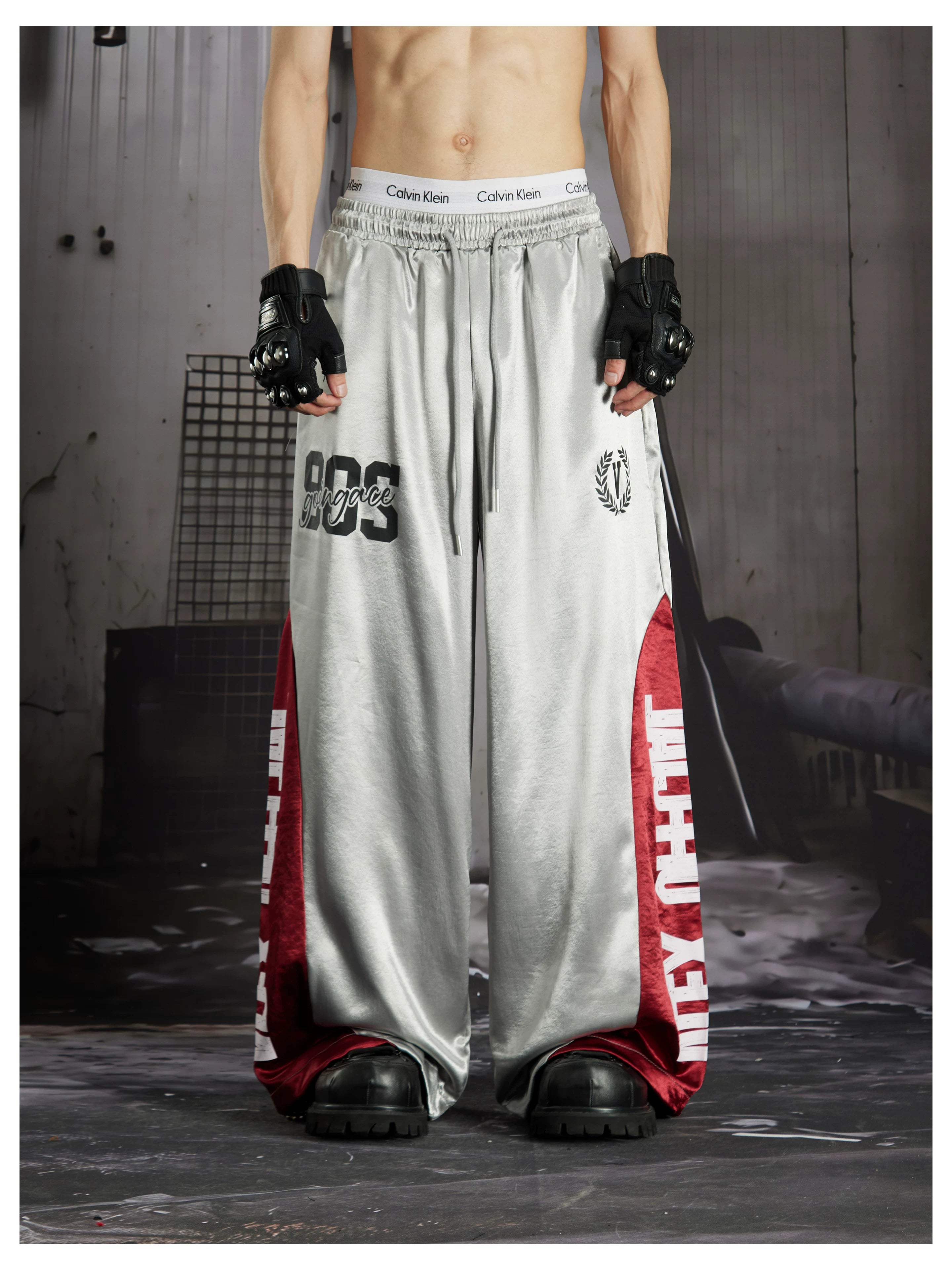 NOMANIAI Street-style casual pants featuring a draped fit, paneling, and a print design.
